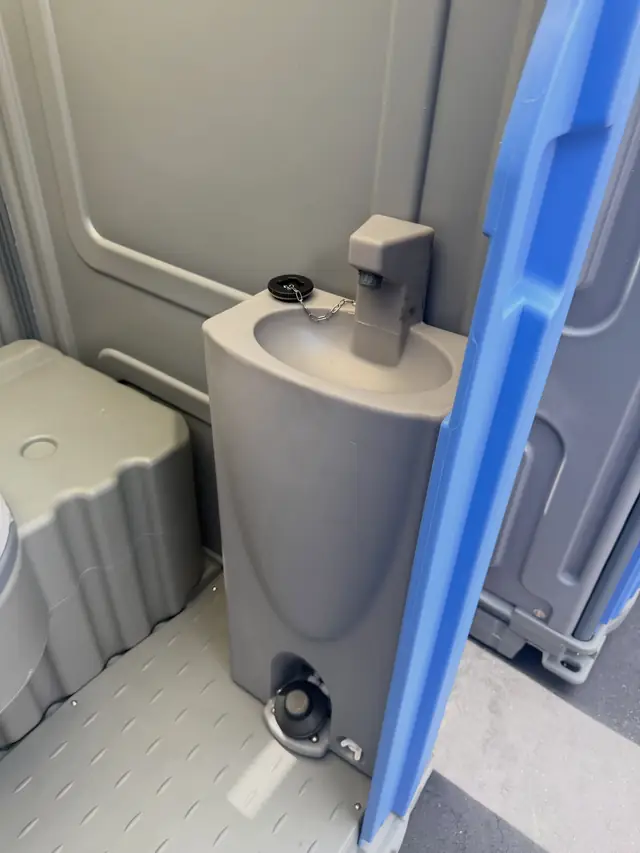 Built-in foot-pump sink inside a deluxe flushing porta potty